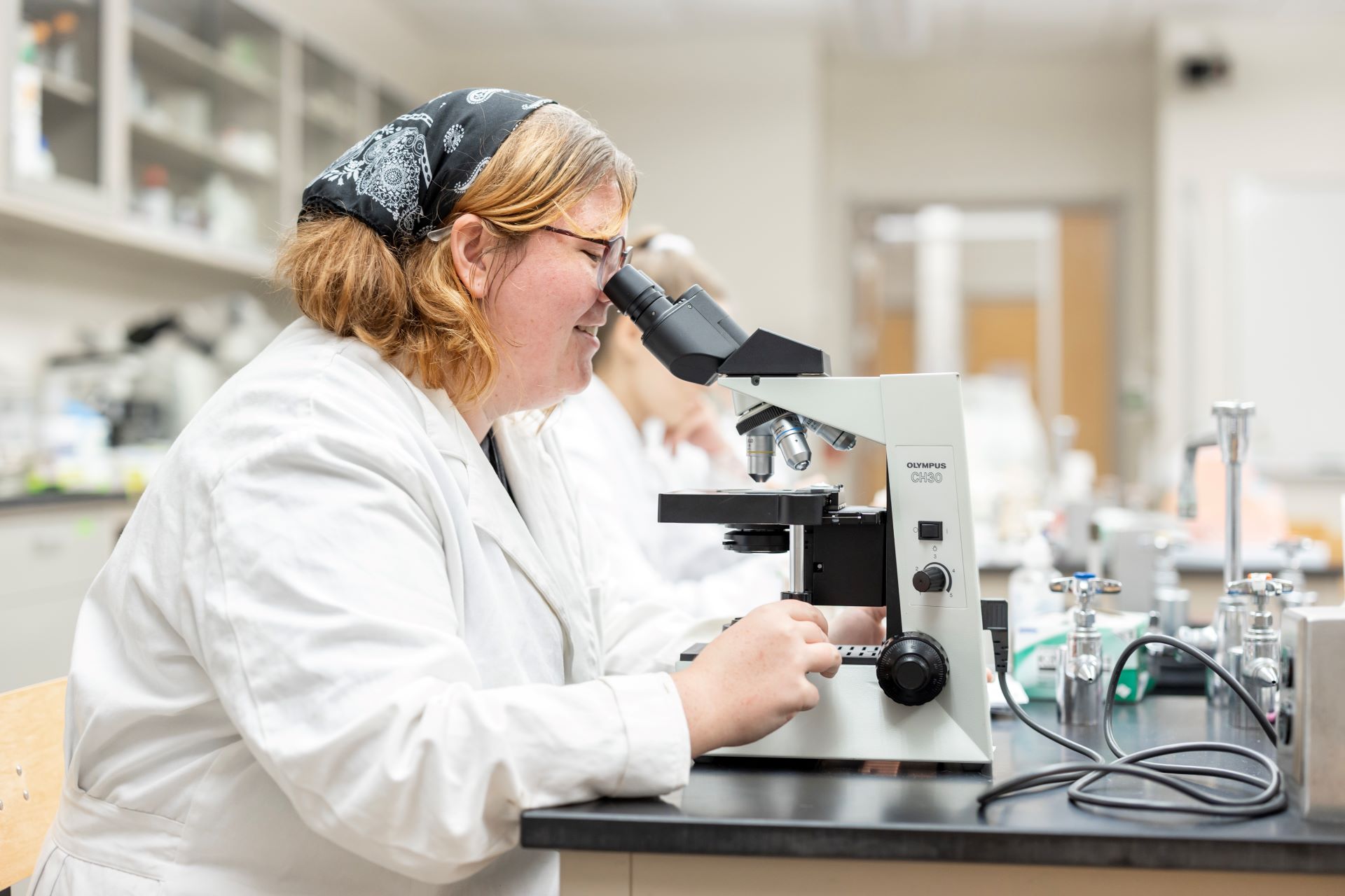 Student looking through a microscope in a classroom